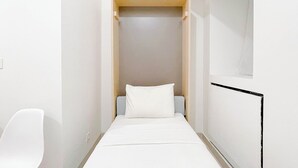 A narrow, walk-in closet with a bed, a chair, and a window. - Studio Apartment (No Kitchen) Near Unhas At Bandaraya - Tallasa City Makassar (Makassar)