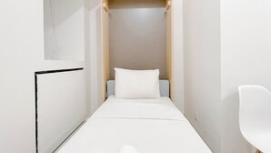 Een smalle inloopkast met een bed aan het einde.