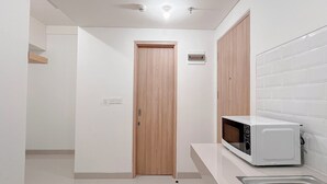 A modern kitchen with white cabinets, a microwave, and a sink. - Minimalist 1Br Combined (No Kitchen) At Bandaraya - Tallasa City Makassar Apartment (Makassar)