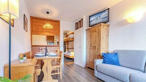 Un espacio habitable compacto con zona de comedor, sofá y televisor.