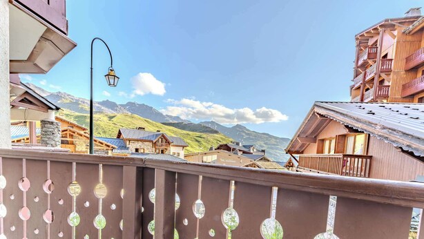 Un pueblo de montaña con edificios de madera tradicionales, cielo despejado y vistas a montañas distantes.