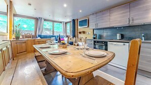 A modern kitchen with wooden cabinets, a dining table set for four, and a built-in oven.