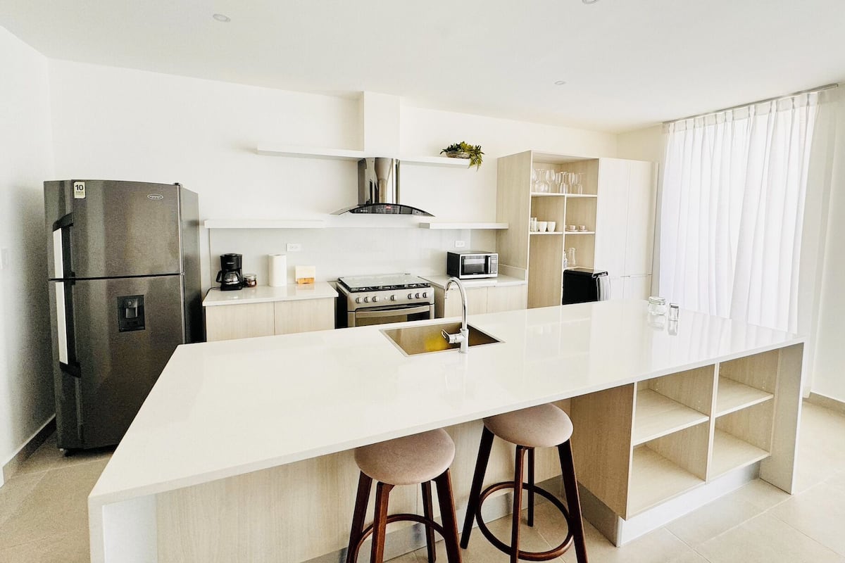 A modern kitchen with a central island, stainless steel appliances, and white cabinetry.