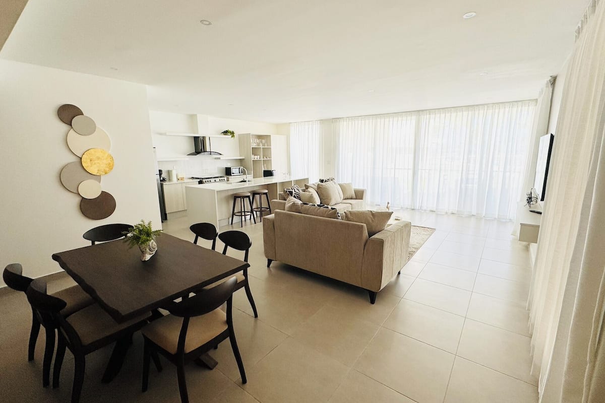 A modern apartment with a dining area, kitchen, and living room.