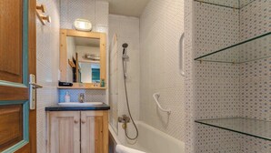 A bathroom with a wooden vanity, a white bathtub, and a shower with a handheld showerhead. - Comfort with Balcony and parking (Val Thorens)