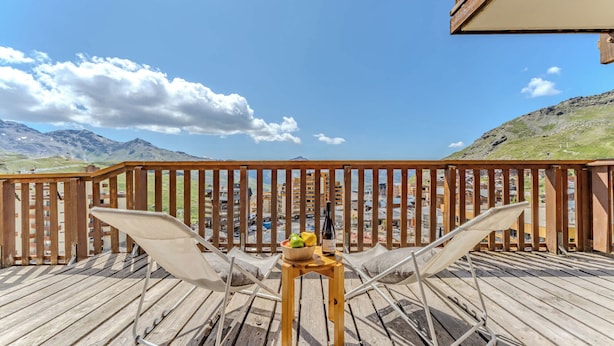 A wooden deck with a view of mountains and a town. - Comfort with Balcony and parking (Val Thorens)