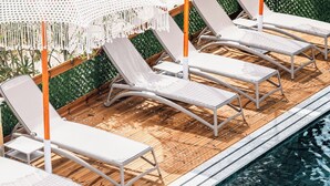 Ett område vid poolen med solstolar och vita parasoller.