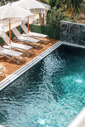 En swimmingpool med liggestole og parasoller.