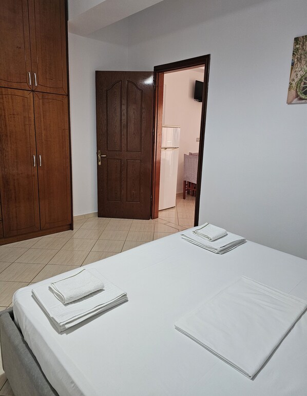 A room with a bed, a wardrobe, and a door leading to another room. - Vila Malo (Ksamil)