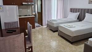 Ένα δωμάτιο ξενοδοχείου με ένα κρεβάτι, ένα γραφείο, μια καρέκλα, μια μικρή κουζίνα και ένα μπάνιο.