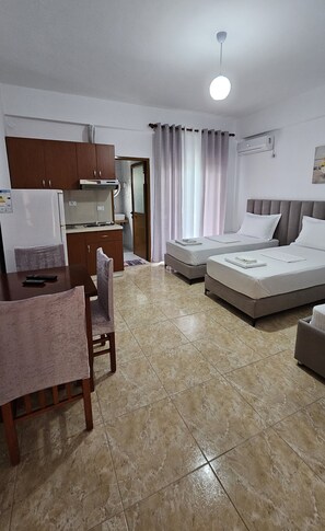 A hotel room with a bed, a desk, a chair, a kitchenette, and a bathroom. - Vila Malo (Ksamil)