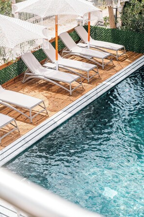 Un espace aménagé au bord de la piscine, avec des chaises longues et des parasols.