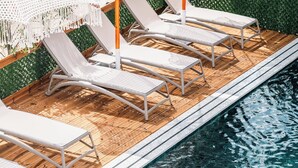 Ett område vid poolen med solstolar och parasoller.