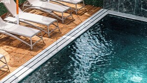 En pool med solstolar och parasoller.