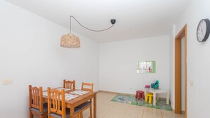 Ein Essbereich mit Holztisch und -stühlen, einer hängenden Lampe und einem farbenfrohen Teppich.