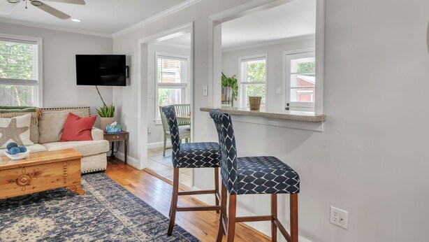 A living room with a sofa, coffee table, TV, and two patterned chairs. - The Oleander Cottage (Wilmington)