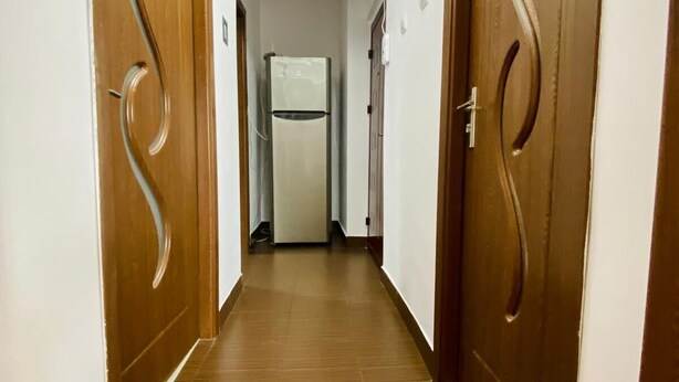 Ein Flur mit Holztüren und einem Kühlschrank im Hintergrund.
