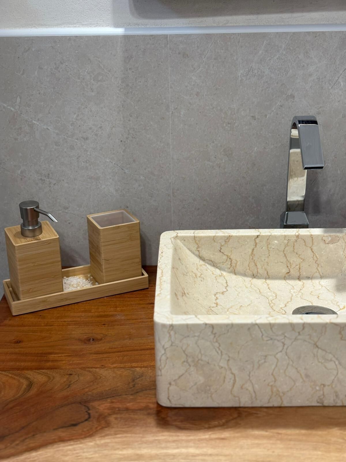 A bathroom with a marble sink, wooden soap dispensers, and a modern faucet.