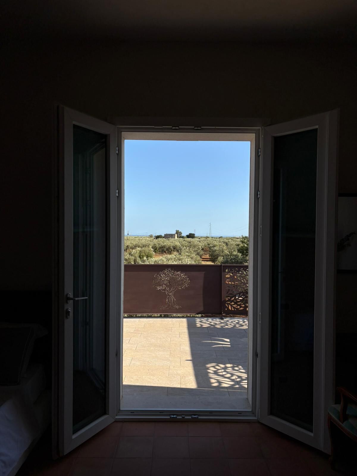An open sliding door leading to a patio with a view of a rural landscape.