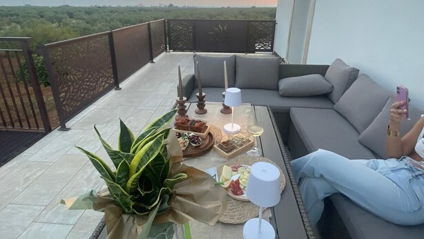 Een terras op het dak met een eethoek, inclusief een tafel met eten en drinken, een bank en uitzicht op het landschap.