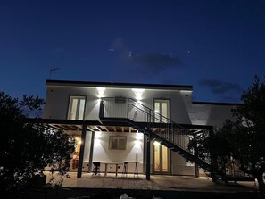 Ein modernes, zweistöckiges Haus mit Balkon, Außenbereich und einer Treppe.