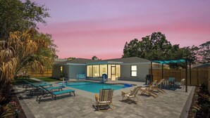 A backyard with a swimming pool, lounge chairs, and a covered patio area. - Cozy Pool House 24 min to Beach, Cozy Pool House 24 min to Beach (Manatee County)