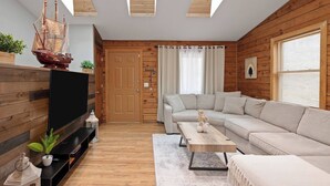 Ein modernes Wohnzimmer mit Holzboden, einem Flachbildfernseher, einer Couch, einem Couchtisch und einem Schiffsmodell.