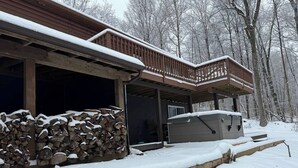 Eine Hütte mit überdachter Veranda, einem Holzstapel und verschneitem Gelände.