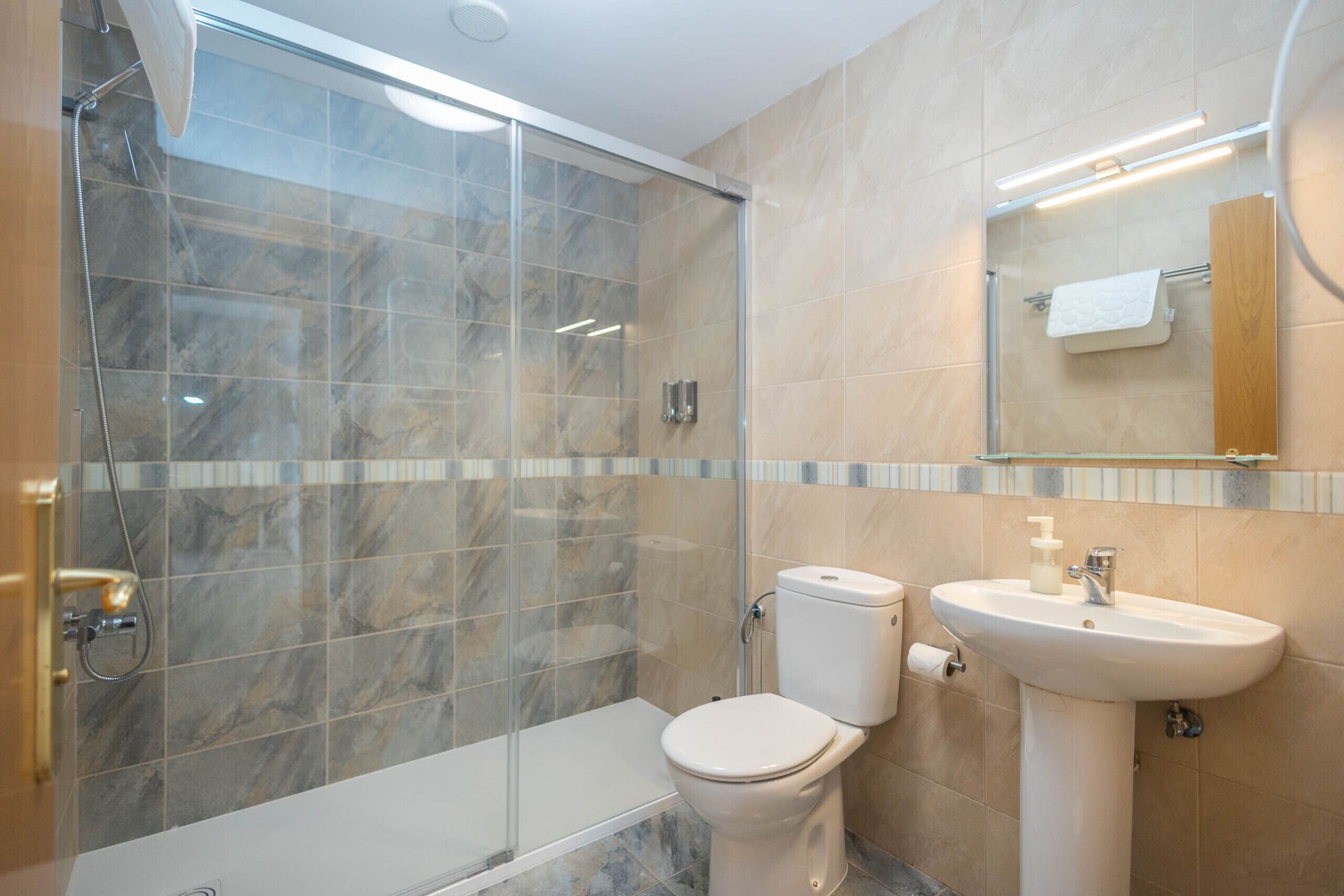 A modern bathroom with a glass-enclosed shower, a toilet, and a sink.