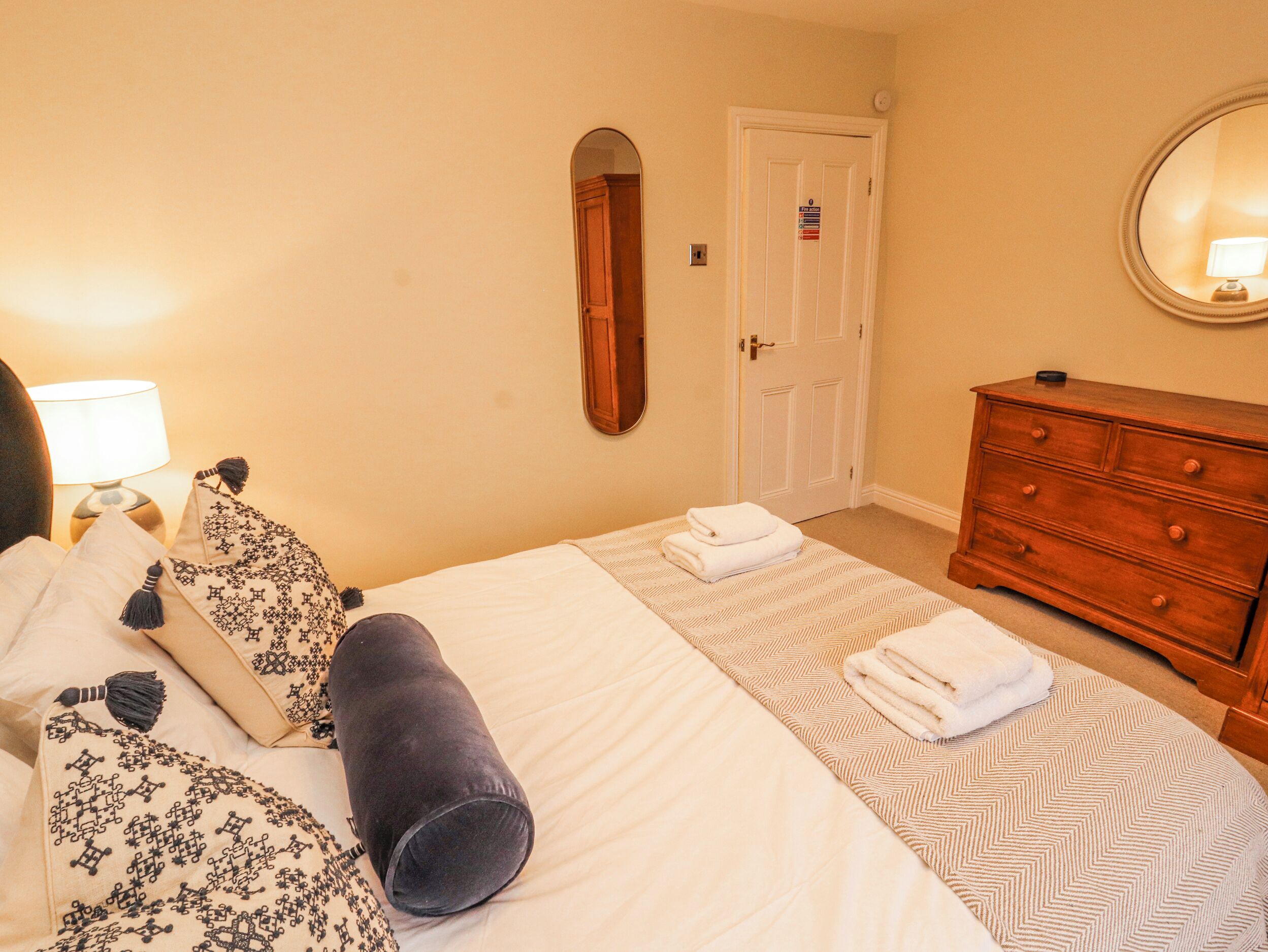 A hotel room with a bed, a dresser, a mirror, and a door.
