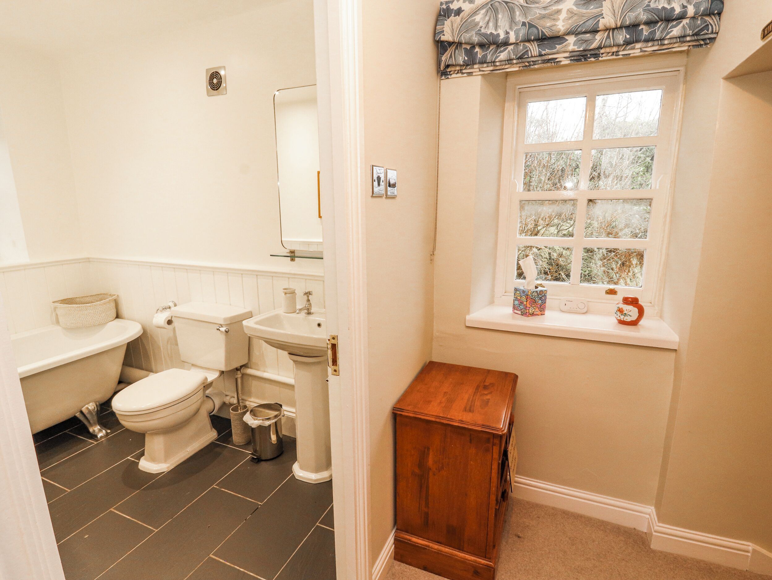 A bathroom with a toilet, sink, and window.