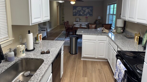 A kitchen with granite countertops, white cabinets, a black stove, and a dining area with a table and chairs. - Perfect 3 bed 2 bath football weekend house. 10 minute walk to the square. (Oxford)