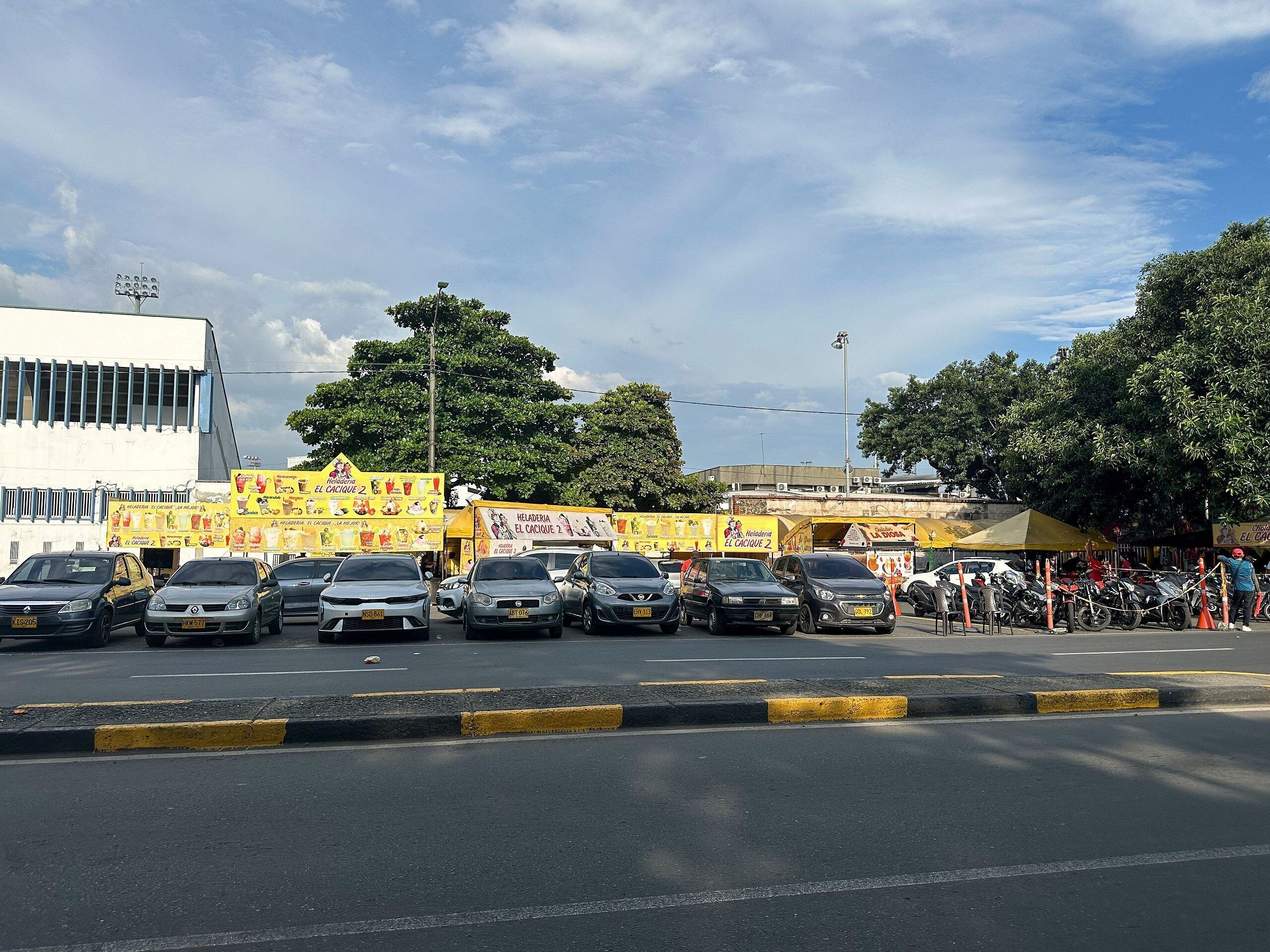A street with parked cars and a building with yellow signage.