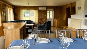 L’intérieur d’un chalet en bois comprend une table à manger pour quatre personnes, un canapé et un coin cuisine.