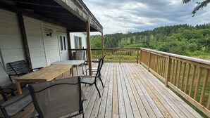 Une terrasse en bois avec une table et des chaises, donnant sur une zone boisée.