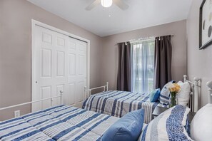 A bedroom with two beds, a white door, a window with curtains, and a ceiling fan. - Pool and fooseball 3-bedroom house in Sarasota (Sarasota)