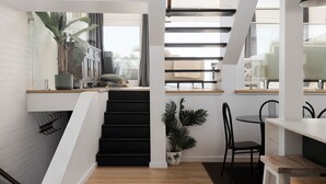 A modern interior with a staircase, a dining area, and a kitchen visible through a window. - The Palms-  9 Pantowora St, Corlette (Corlette)