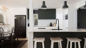 A modern kitchen with a central island, black cabinets, and pendant lighting. - The Palms-  9 Pantowora St, Corlette (Corlette)