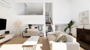 A modern living room with a flat-screen TV, a sofa, a coffee table, and a dining area with a table and chairs. - The Palms-  9 Pantowora St, Corlette (Corlette)