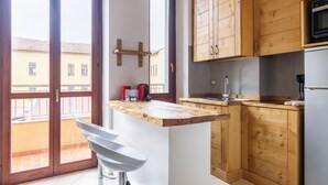 A kitchen with wooden cabinets, a built-in microwave, and a large window. - Cozy apartment in Bovisa (Milano)