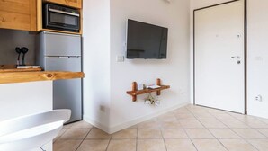 A modern kitchen with wooden cabinets, a built-in oven, and a wall-mounted TV. - Cozy apartment in Bovisa (Milano)