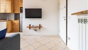 A modern kitchen with wooden cabinets, a built-in oven, and a flat-screen TV mounted on the wall. - Cozy apartment in Bovisa (Milano)