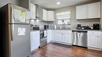 A kitchen with white cabinets, stainless steel appliances, a microwave, stove, and dishwasher.