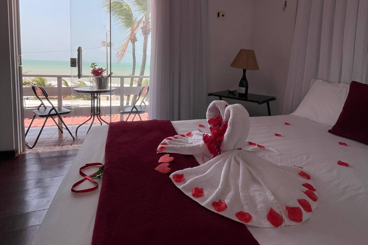Une chambre d’hôtel avec un lit, une table et une chaise, située près d’une porte-fenêtre coulissante.