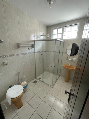 Ein Badezimmer mit Duschkabine, Toilette und Waschbecken mit Spiegel.