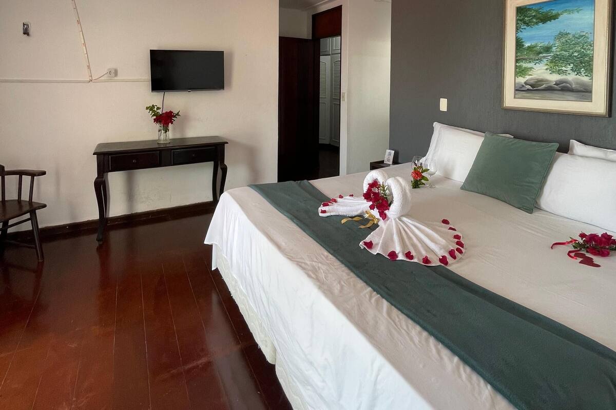 Une chambre d’hôtel avec un lit, un bureau, une télévision et un tableau au mur.