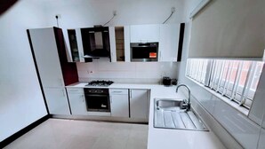 Eine moderne Küche mit weißen Schränken, einem Gasherd, einem Backofen und einer Spüle.