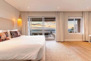Camera da letto con un letto grande, vista mare e un balcone con tavolo e sedie.