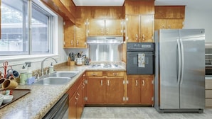 A kitchen with wooden cabinets, stainless steel appliances, a window, and a granite countertop. - Cozy Convenient Mid-Century Apt! (Chattanooga)