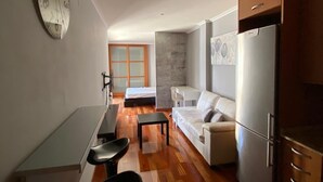 Eine moderne Küche mit Kühlschrank, ein Essbereich mit Tisch und Stühlen sowie ein Wohnbereich mit Sofa.